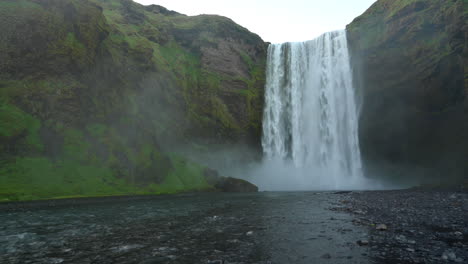 Waterfall-of-Skogafoss,-Ring-Road-in-Iceland,-tripod-shot-from-the-river