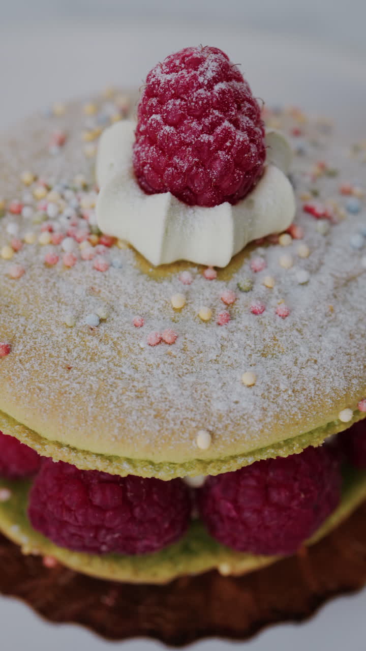 Close up of a giant macaron with raspberries and cream on a white plate. Vertical