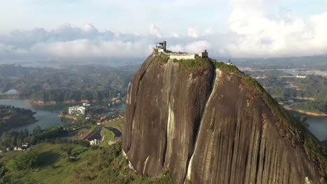 cinematic circle pan aerial shot of el peñol rock at guatapé colombia during golden hour sunset