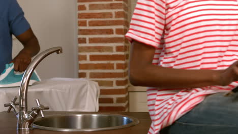 man ironing while woman using tablet