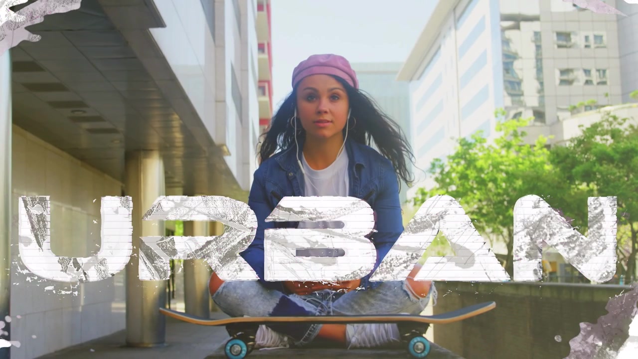 Giovane donna seduta su uno skateboard che usa lo smartphone in ambiente urbano