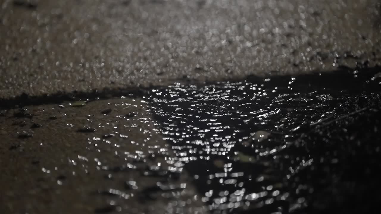 Grimy Puddle on Sidewalk in Rainfall with Rippling Water