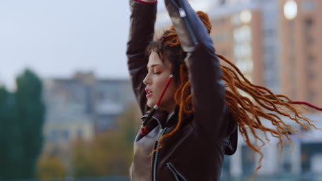 red hair woman dancing outdoor. active girl spinning outside on urban background