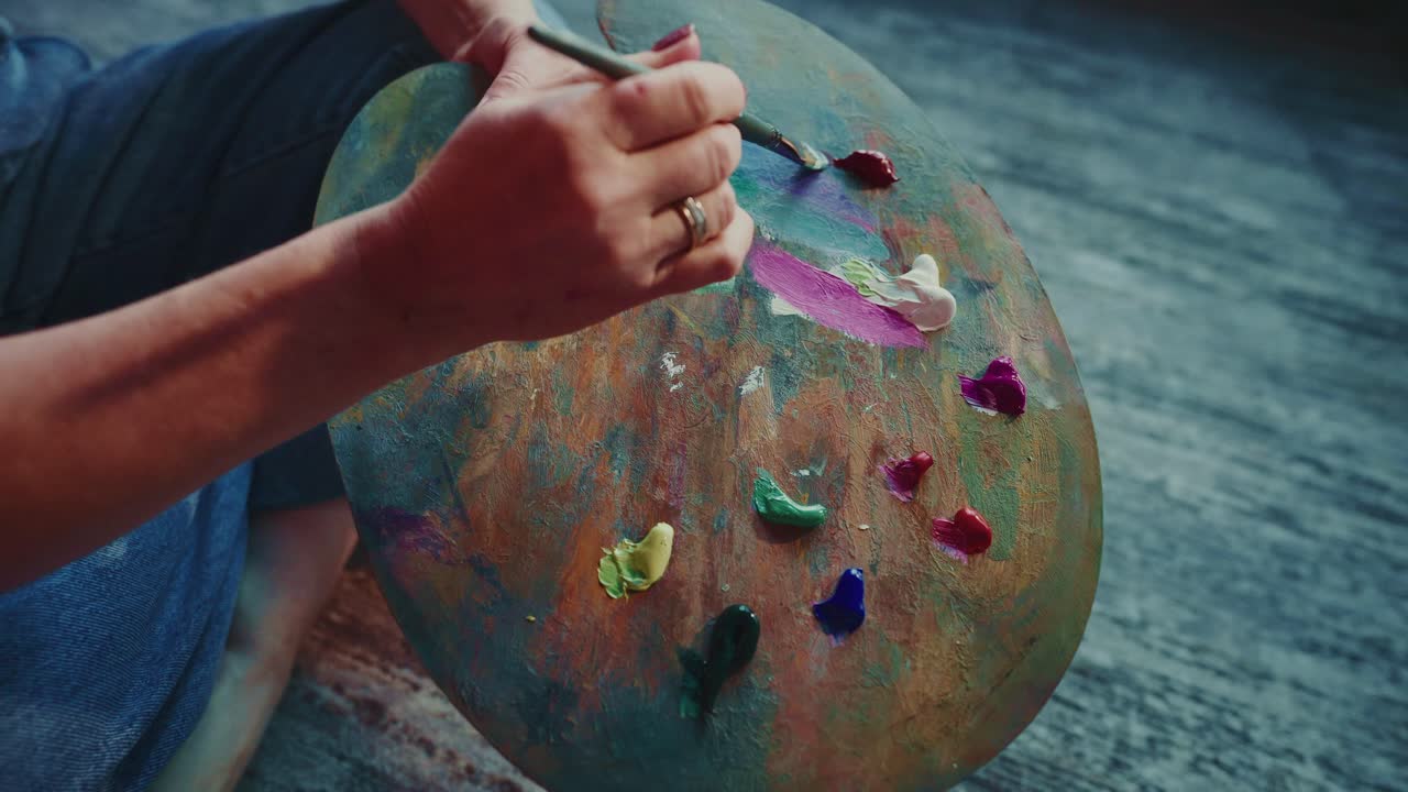 Close-Up of Artist's Hands Mixing Colorful Paints on a Palette