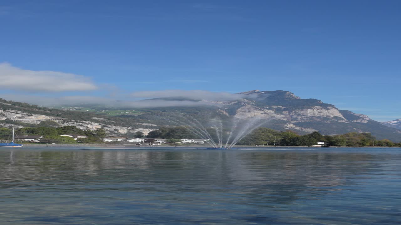 Lake Walensee Switzerland fountain shoots high above calm blue water with Churfirsten peaks behind vertical view