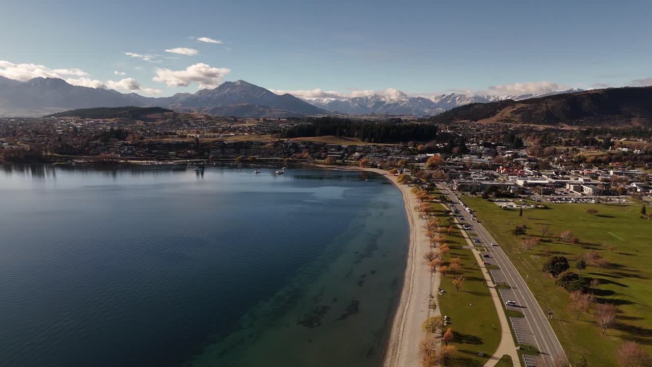Scenic aerial over Lake Wanaka at sunset, showing town and Southern Alps mountain range in background, South Island, New Zealand