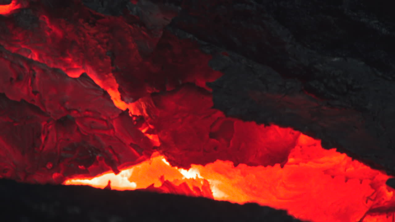 暗い火山岩を流れる鮮やかな赤い溶岩