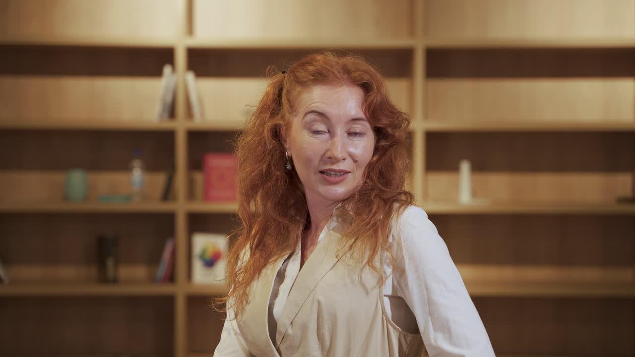 매력적인 빨간 머리 여자가 숨을 쉬고 카메라로 다소 도전적으로 보입니다.