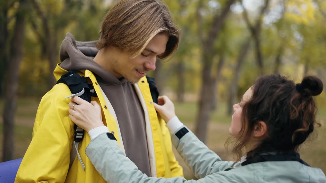 пара путешествует с рюкзаками, подруга проверяет ее мужскую одежду, прежде чем идти дальше