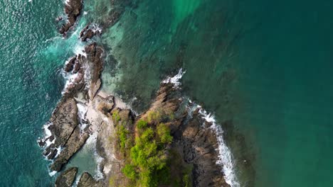 Aerial-top-down-view-of-a-waves-crashing-on-a-rocky-cliff-in-Playa-Blanca,-co0S