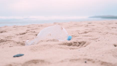 Una-Sola-Botella-De-Agua-De-Plástico-Tirada-En-La-Playa-De-Arena