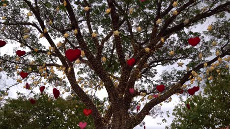 Red hearts hanging on a tree with many paper stars and lights twinkling at night. valentine's day concept