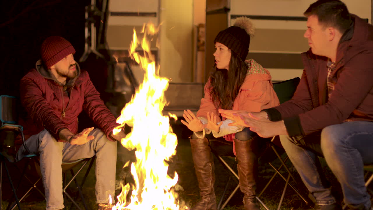 imágenes de mano de amigos calentando su mano en el fuego del campamento en una fría noche de otoño