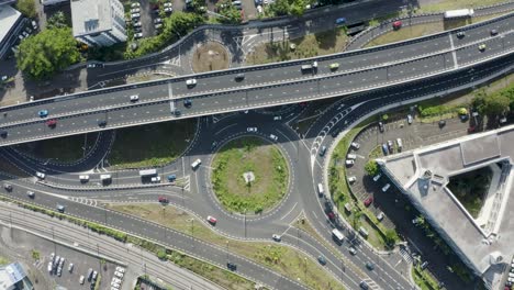 descending aerial top down shot of traffic on highway and roundabout during sunny day - vacoas phoenix, mauritius