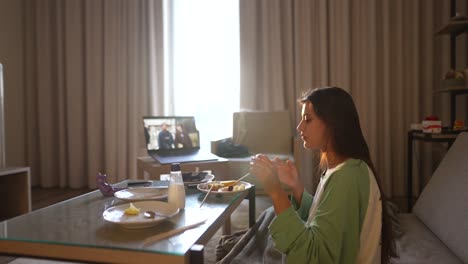 mujer comiendo en casa durante una llamada de video