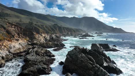 Luftaufnahme-Von-Wellen,-Die-Gegen-Felsen-Bei-Big-Sur-Schlagen,-Blick-Auf-Die-Berge-Von-Santa-Lucia