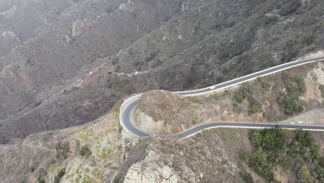 Luftaufnahme-Eines-Weißen-Autos,-Das-Auf-Einer-Kurvenreichen-Straße-An-Einem-Felsigen-Berg-Auf-Teneriffa,-Kanarische-Inseln,-Fährt