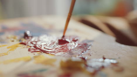 Blending-Paint-Colors-with-Brush-on-Wooden-Palette