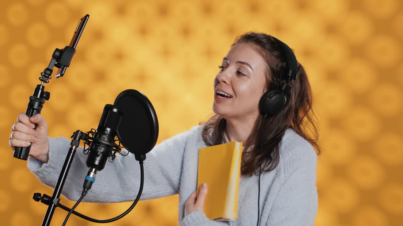 Influencer gioioso che filma la recensione di un libro con un selfie stick, sfondo in studio