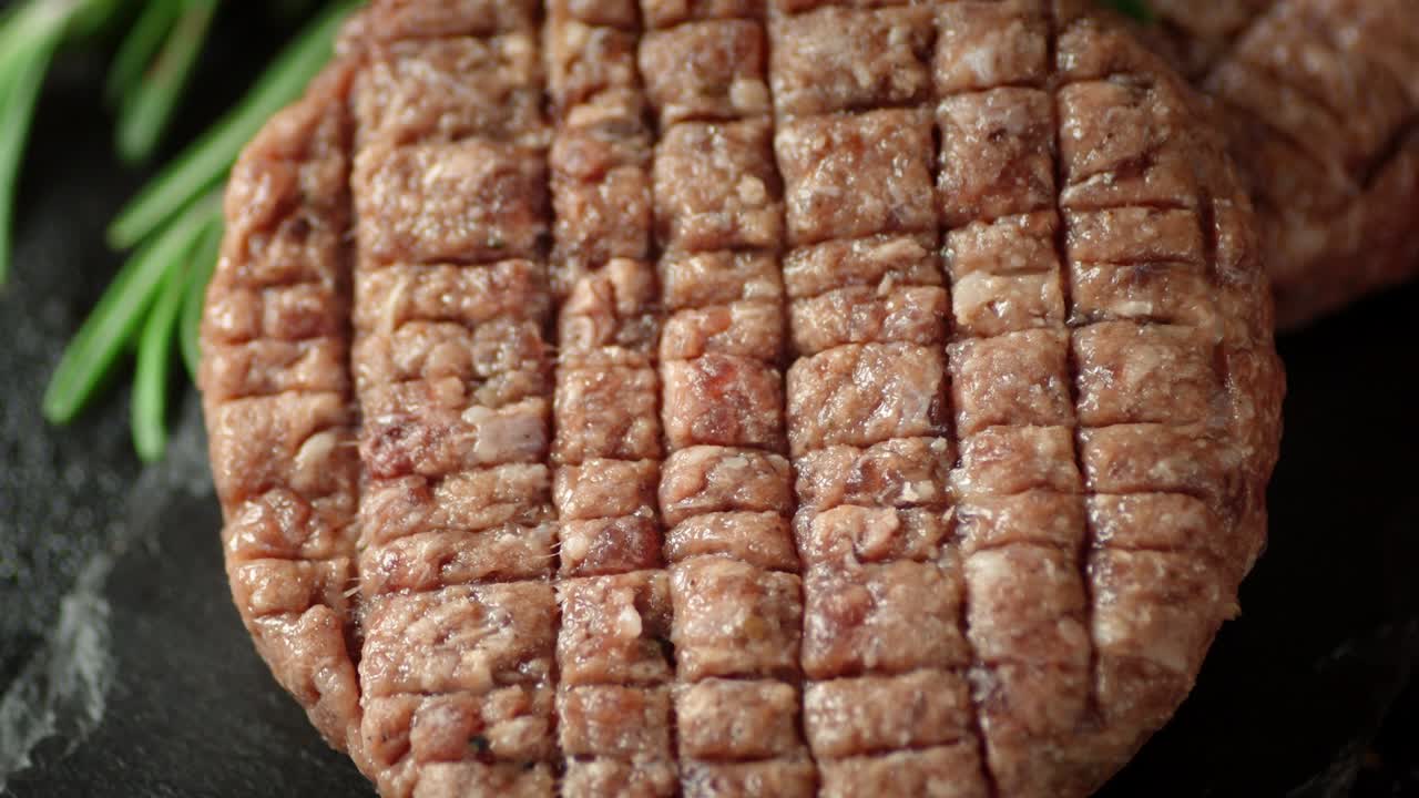 la hamburguesa de carne cruda en una tabla de piedra gira.