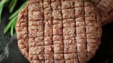 raw beef burger on a stone board rotates.