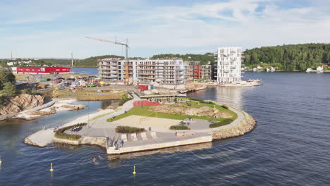 Vista-Aérea-Del-Parque-Infantil-Lokholmen-Y-Zona-De-Baño-Con-Un-Edificio-En-Construcción-Al-Fondo-En-Arendal,-Noruega