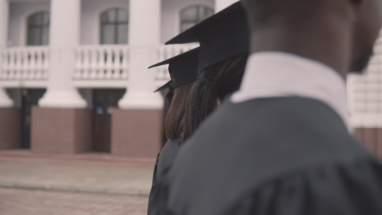 Pretty Girl Graduate Student In Gown And Cap In A Row Looking At The Camera And Smiling
