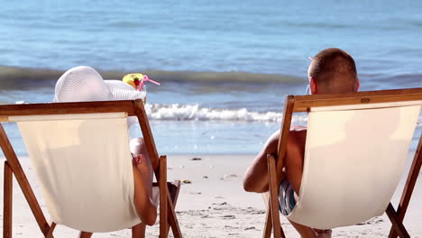 una pareja bebiendo un cóctel en la playa.