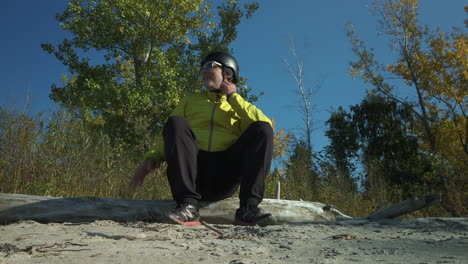 helmeted cyclist sitting down on a log at the beach