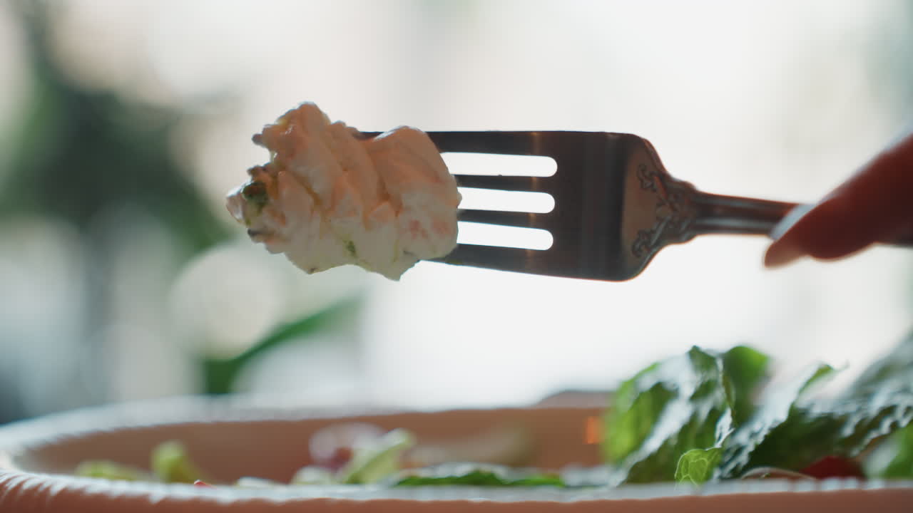 Gaffel løfter cremet bid over salat i blødt naturligt baggrundslys, lav dybdeskarphed viser frisk salat og mynte, hjemmelavet dressing glinsende på skålkant, langsom filmisk bevægelse fanger roligt hjem