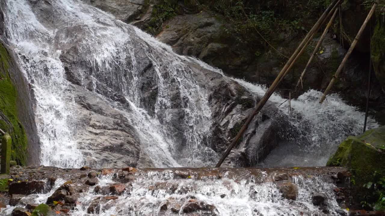 Fossekaskader som faller ned i sakte film inne i frodig jungel i Thailand