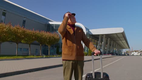 portrait of senior retired man tourist near airport terminal waiting boarding on plane for traveling