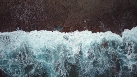 rising bird's eye view of ocean waves crashing against maré island coast