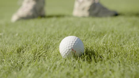 Golf-ball-on-grass-field-near-practicing-player