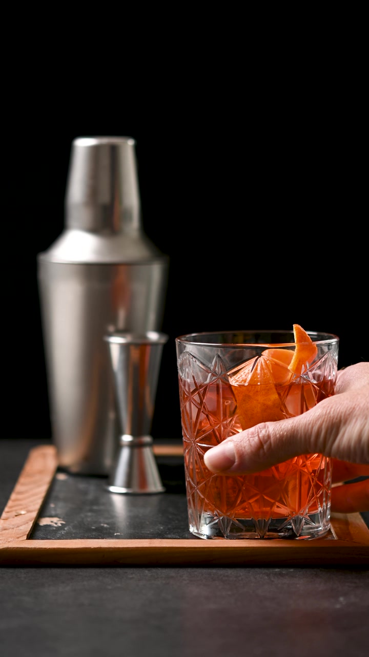 Mano che prende un cocktail Old Fashioned da un vassoio di servizio
