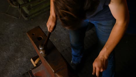 female metalsmith molding horseshoe in factory 4k