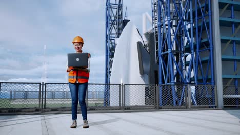 cuerpo lleno de ingeniera femenina asiática con casco de seguridad trabajando en una computadora portátil mientras está de pie con el transbordador espacial