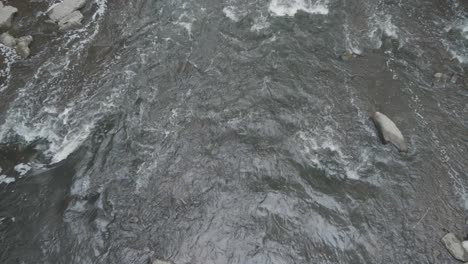 Wissahickon-Creek,-water-flowing-over-stones,-overhead-shot-from-Ridge-Avenue-bridge