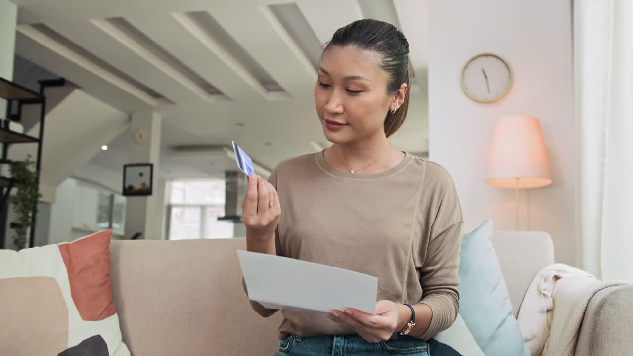 Asian Woman Looking at Her New Credit Card at Home