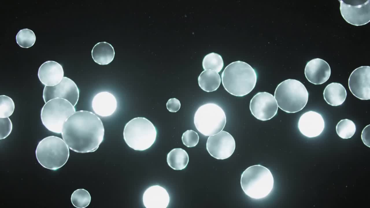 Starting with scattered discs, glowing discs drifting across black void, passing bright lights