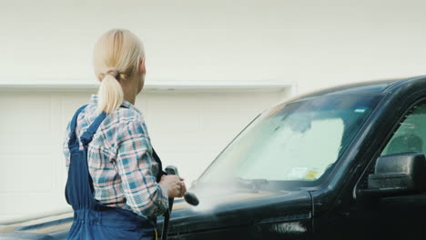 a woman washing my car in the backyard of her house on the background of the doors to the garage