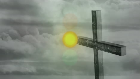 bright sun shining through clouds behind wooden cross standing against sky