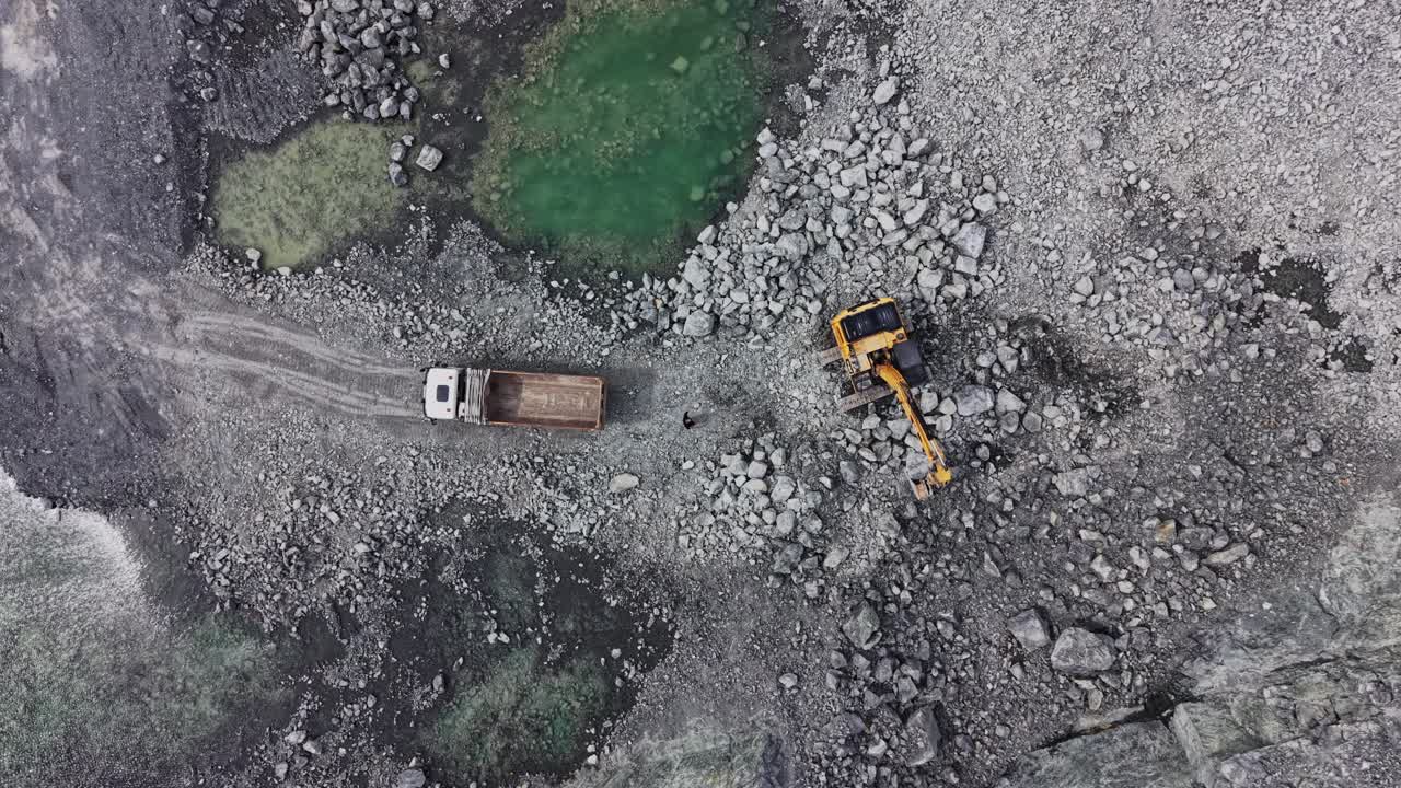 Luftfoto af gravemaskine, der læsser sten i en dumper i et stenbrud.
