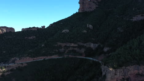 Vista-Aérea-Hacia-Los-Vehículos-Que-Conducen-A-La-Sombra-De-Montserrat-Frondoso-Bosque-Pintoresco-Camino-De-Montaña