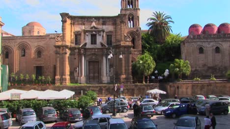 many cars are parked in front of a religious building made of stone palermo italy