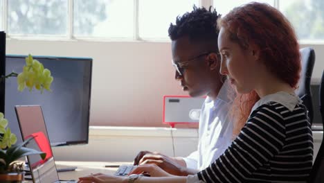side view of young mixed-race business team working on laptop and desktop pc in a modern office 4k