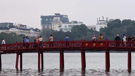 people walking on a red bridge over water