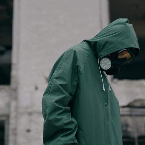 unrecognizable person in safety suit and respirator. human wearing hazmat suit looking for somebody on the background of destroyed building. chemical attack