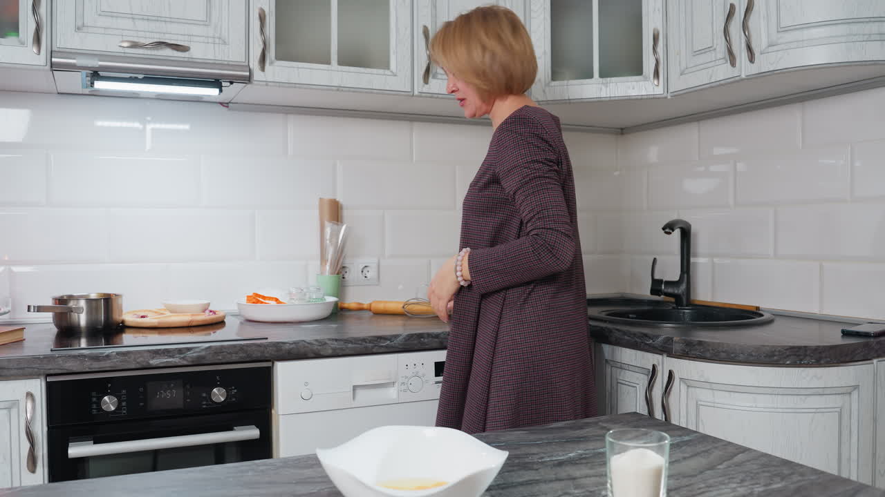 현대 주방에서 베이킹을 준비하는 여성, 그녀는 트위스터,  달과 함께  그과 설탕 한 잔을 카운터 에 앉아있는 동안 사려 깊게 나타납니다.