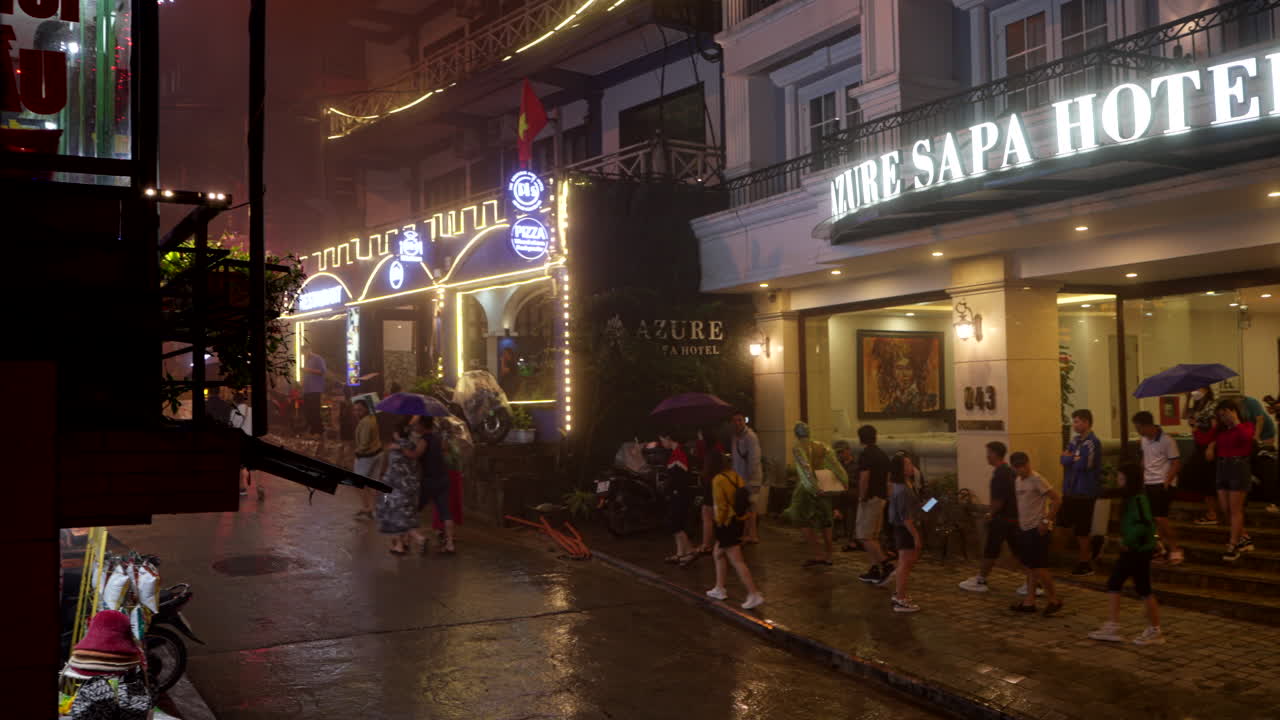 Rainy Night in Sapa, Vietnam: Tourists and Locals Under Umbrellas